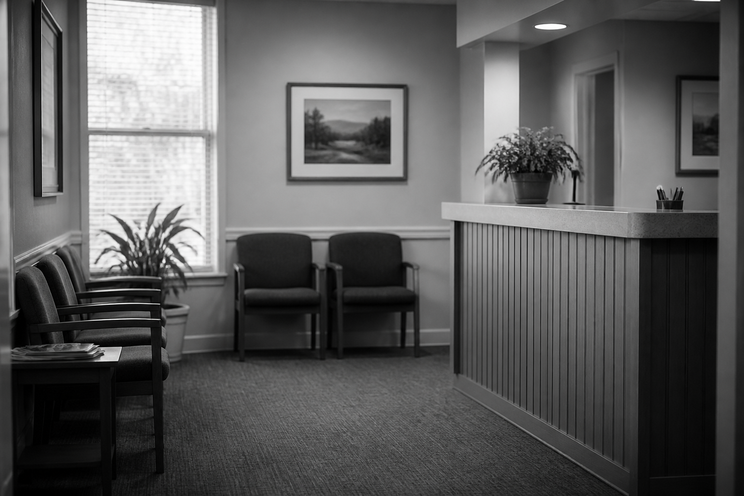 Quiet reception seating and counter in an established practice, photographed in black and white.